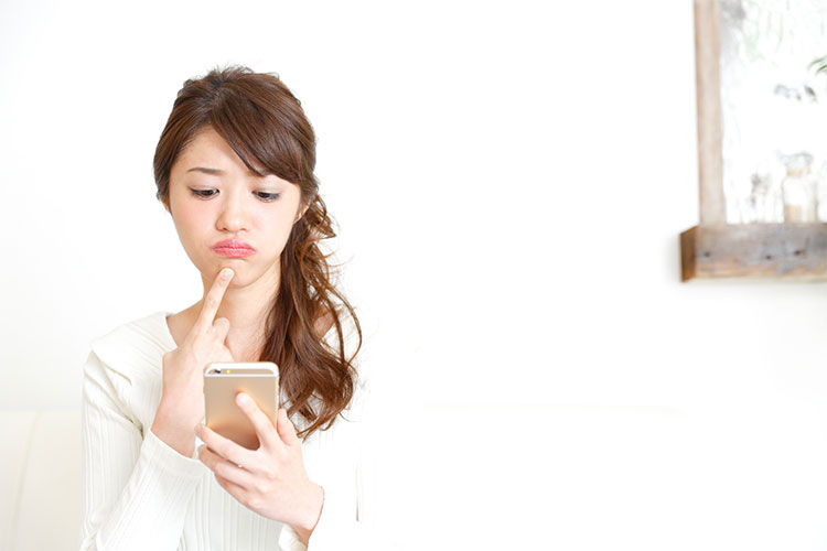 バッテリー交換が必要なiPhoneを手に持って困っている顔の女性
